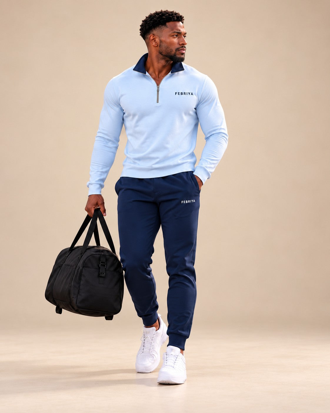 Man in a powder blue and navy set carrying a gym bag in a studio