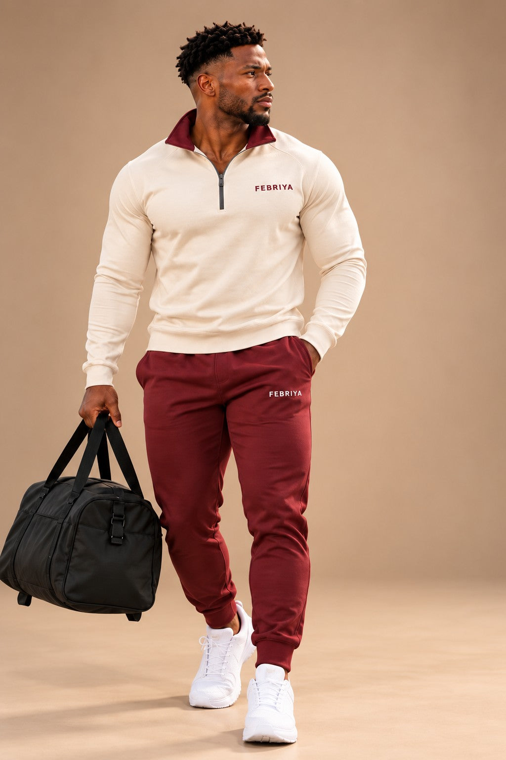 Man in an ivory and ember set carrying a gym bag in a studio